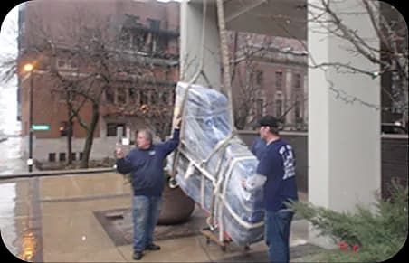 Grand piano being lifted along building exterior